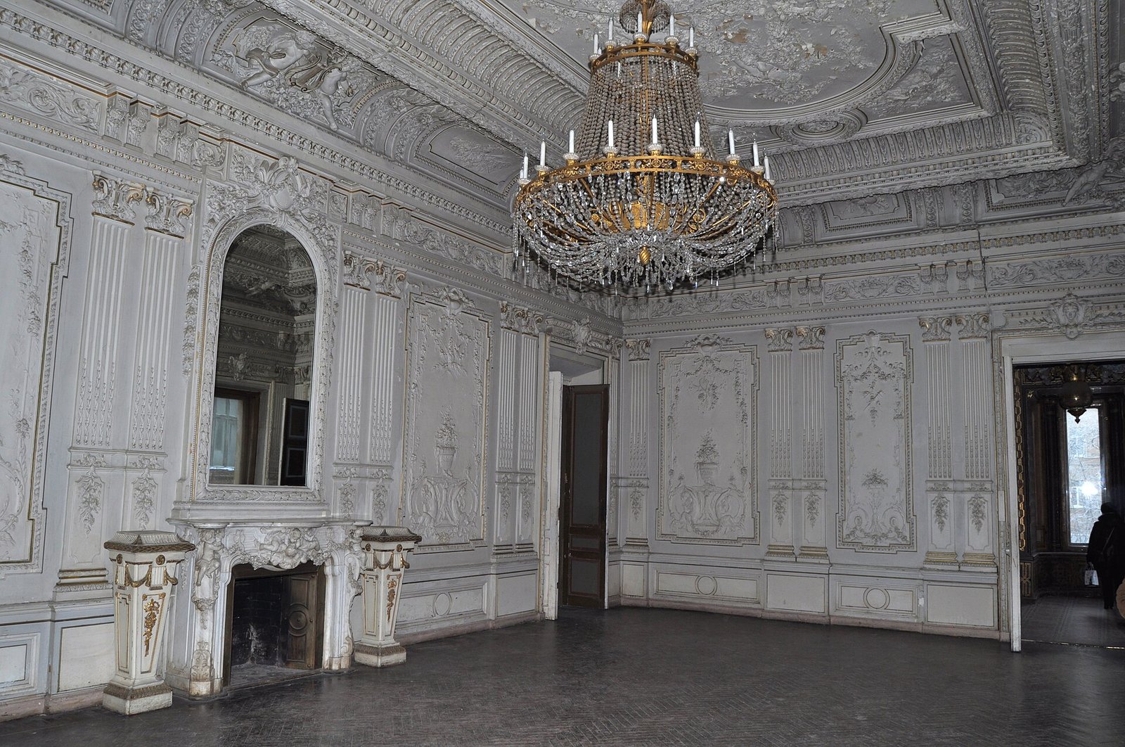 A room with white stucco, a chandelier and a fireplace