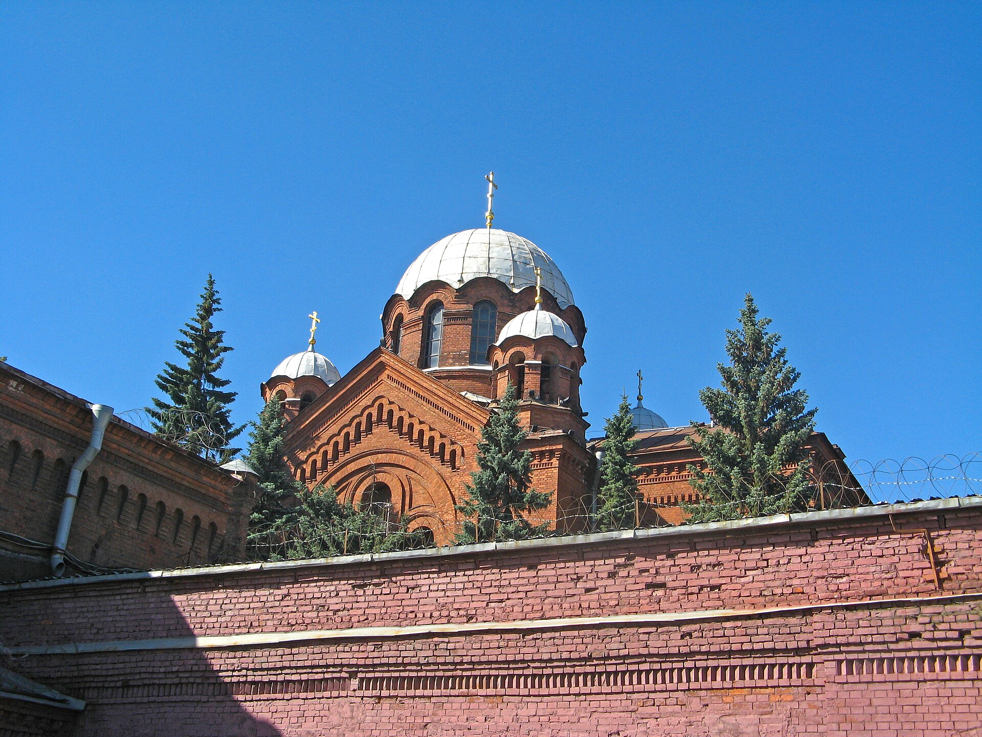 Купола церкви Александра Невского над кирпичной стеной комплекса «Кресты»